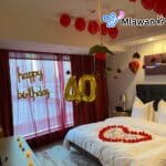 Hotel room decorated with heart-shaped flower petals and red balloons