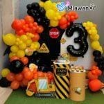 Construction-themed birthday setup with toy trucks and number balloon