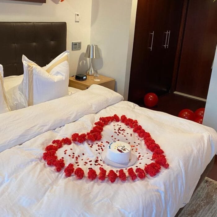 Hotel room decorated with heart-shaped flower petals and red balloons