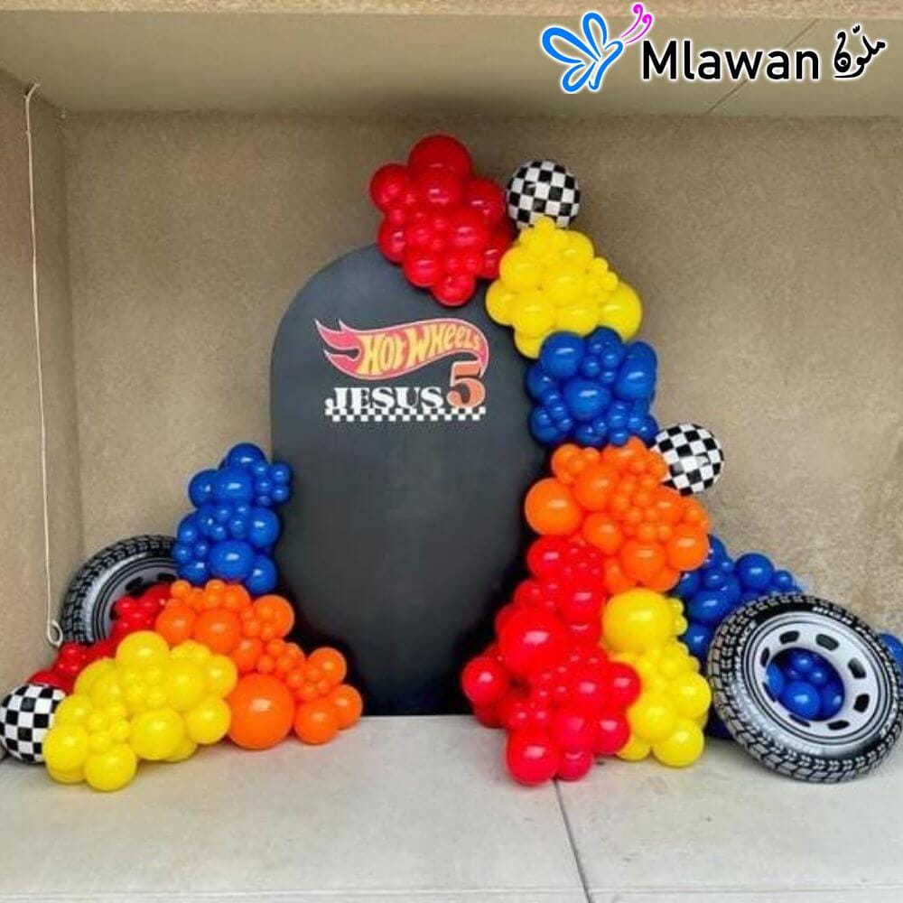 Race car-themed birthday decoration with colorful balloon garland and backdrop. Race car-themed birthday decoration with colorful balloon garland and backdrop.