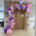 Baby girl hospital room decorated with balloon arches and personalized name banners