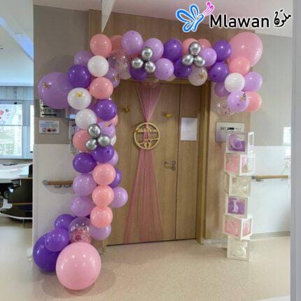 Baby girl hospital room decorated with balloon arches and personalized name banners