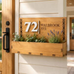 Personalized wooden house number sign with planter box welcomes guests.